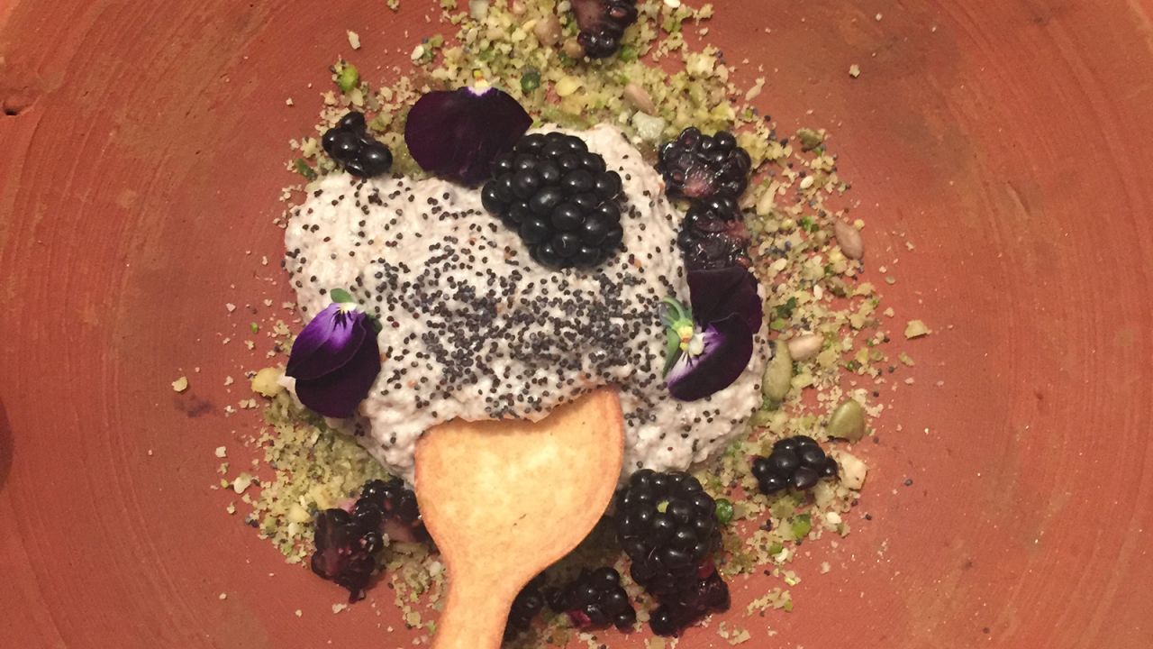 Menu items, like this dessert of blackberries, coconut and chia mouse with raw crumble, are served in earthenware dishes and eaten with edible cutlery.