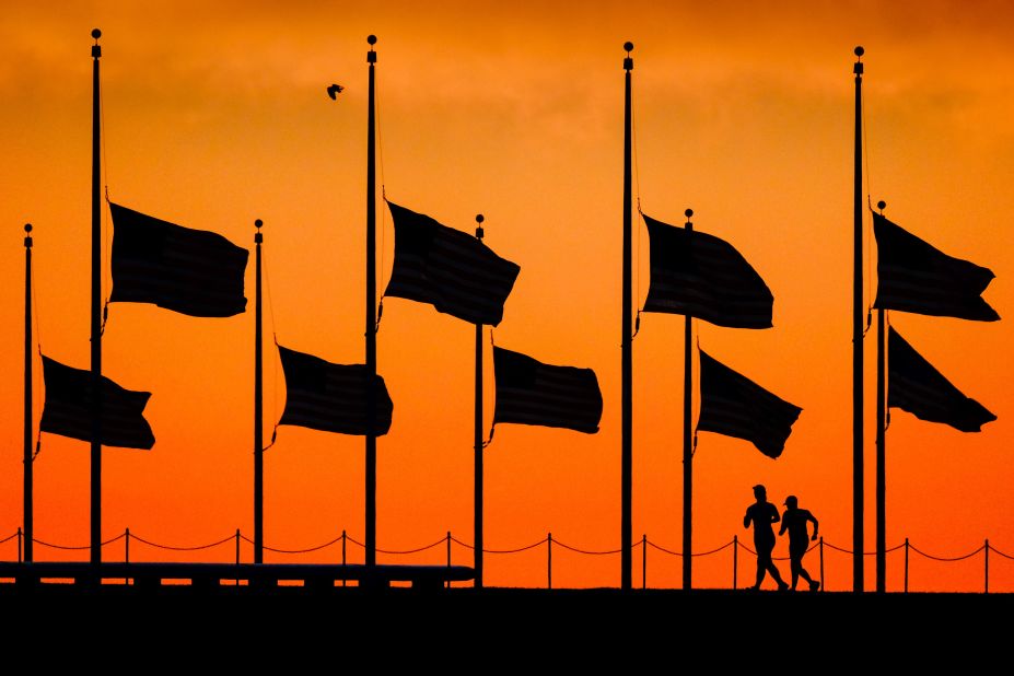 Runners pass under half-staff flags at the Washington Monument on June 13.