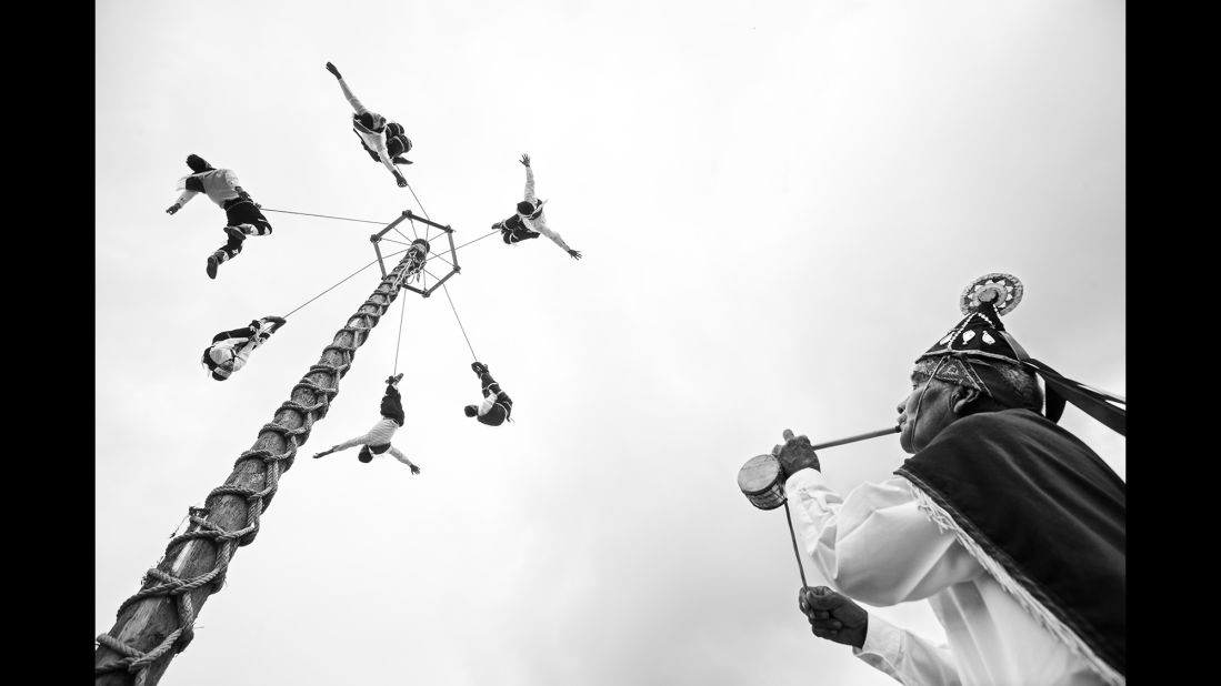 Young voladores descend from a pole while their teacher plays the flute and drum.