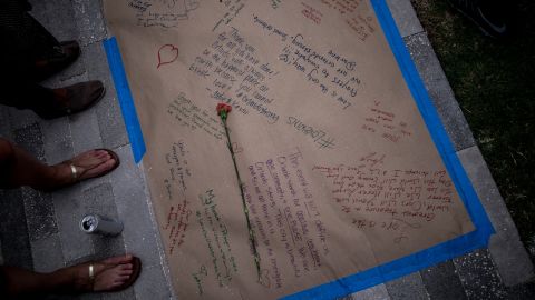 A flower is placed on a long sheet of paper adorned with heartfelt messages.