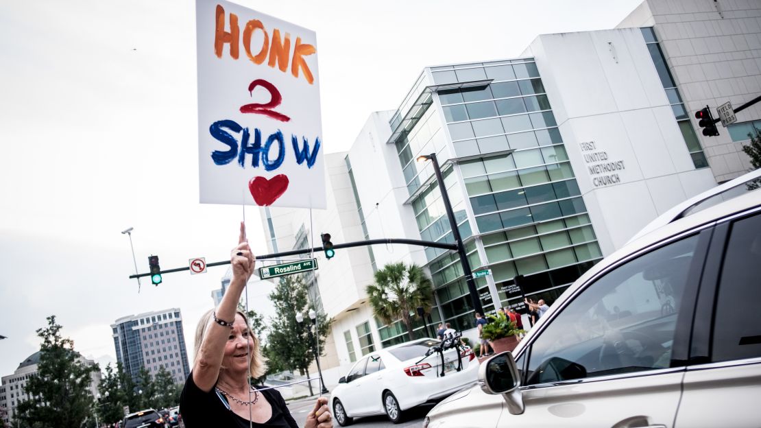 A woman holds up a sign urging solidarity in downtown Orlando on Monday. The community showed signs of resilience.