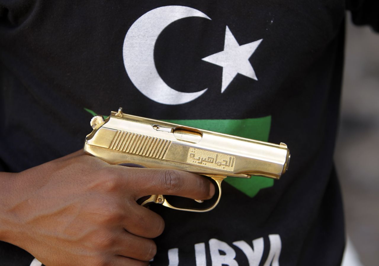 A Libyan fighter holds a golden gun found in the compound of Libya's ousted leader Moammar Gadhafi, in Bab al-Azizizyah, Tripoli, on September 25, 2011.