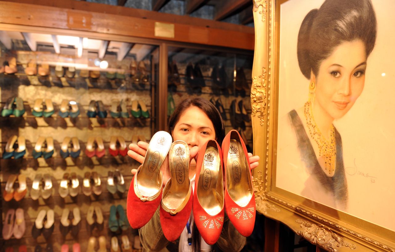 A museum employee displays some of the hundreds of shoes belonging to former Philippine first lady Imelda Marcos, next to her portrait (R) at the shoe museum in Manila on September 26, 2012. 