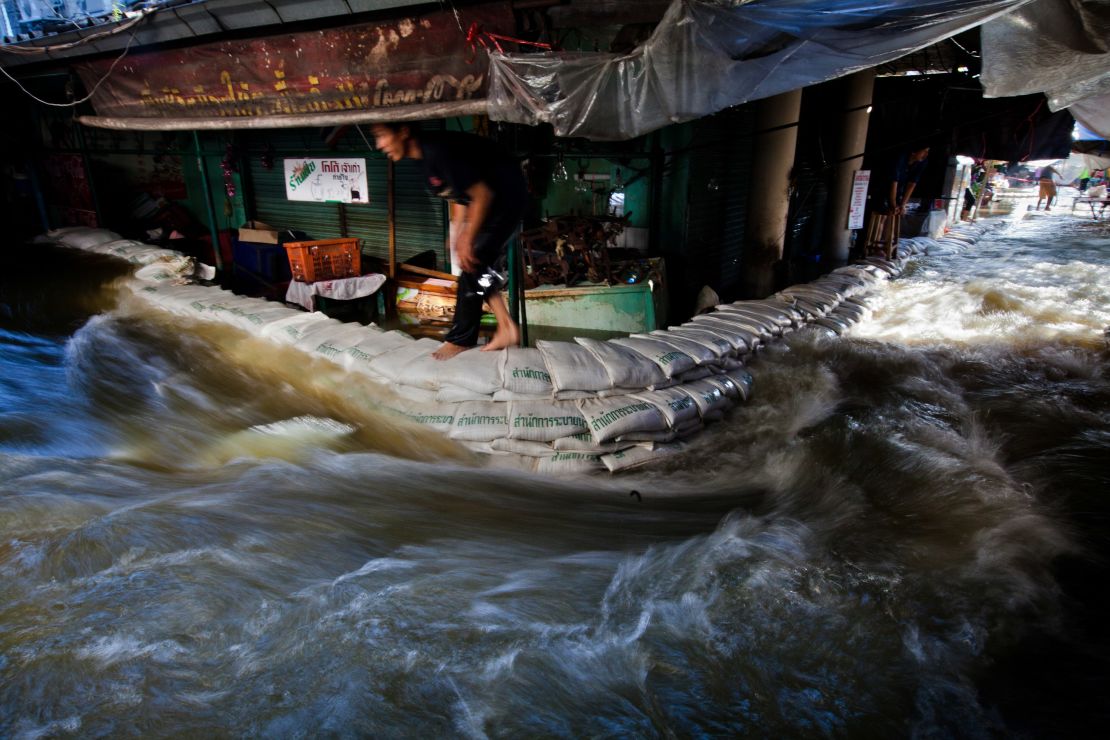 Flood waters rush through a market near to the overflowing Chao Phraya River nearby on October 29, 2011 in Bangkok.