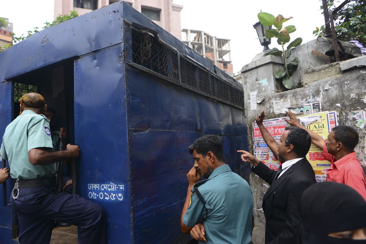 The arrested men try to talk with relatives and lawyers from a prison van outside court.