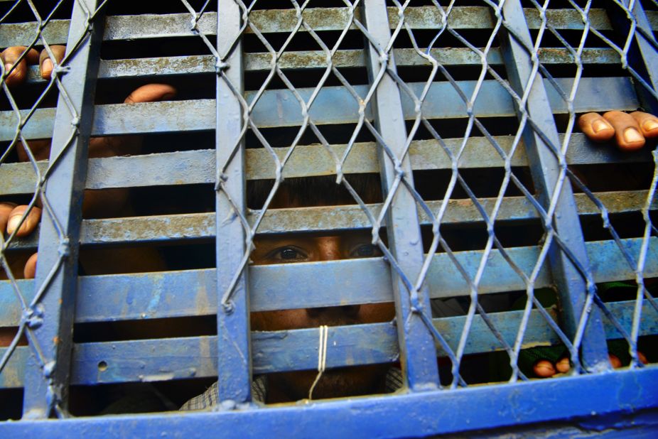 A detained Bangladeshi man looks out from inside a police prison van. 