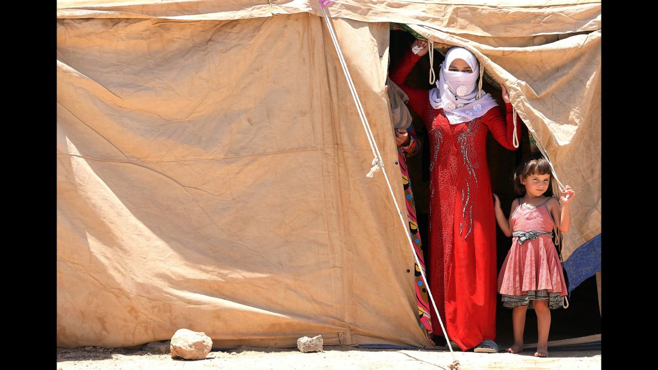Iraqis who have been displaced from their homes peer out of a tent at a camp outside Falluja on Tuesday, June 14.