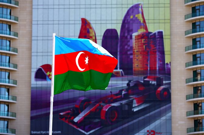 The Azerbaijan flag flutters in front of a poster promoting the European Grand Prix in Baku. 