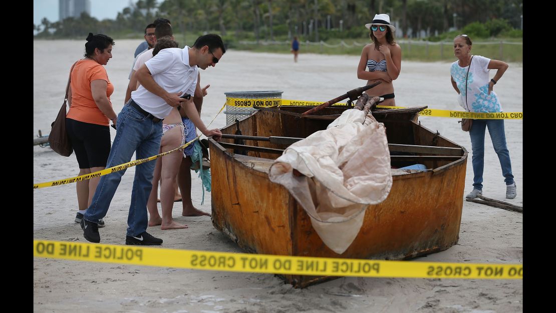 People look at a Cuban migrant boat that brought 12 people and a dog to the beach on September 15, 2015 in Miami Beach, Florida under the previous wet-foot, dry-foot policy.