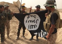 Group of Iraqi soldiers proudly pick up ISIS flag left behind