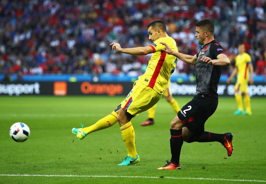 Ovidiu Hoban of Romania shoots at goal under pressure of Andi Lila of Albania.