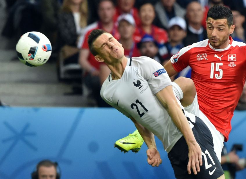France's defender Laurent Koscielny heads the ball next to Switzerland's midfielder Blerim Dzemaili .