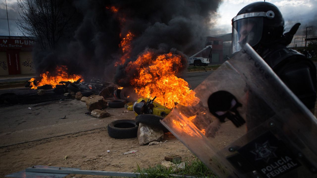 An officer walks past burning debris during <a href="http://www.cnn.com/2016/06/20/americas/oaxaca-mexico-clashes/index.html">deadly clashes between striking teachers and police</a> in Oaxaca, Mexico, on Sunday, June 19. The violence came after seven days of protests disrupting traffic on a major highway connecting Oaxaca to Mexico City, the government said.