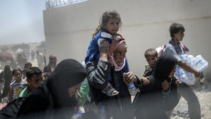Syrians fleeing the war walk towards the border gates at the Akcakale border crossing, in Sanliurfa province on June 15, 2015. Turkey said it was taking measures to limit the flow of Syrian refugees onto its territory after an influx of thousands more over the last days due to fighting between Kurds and jihadists. Under an 'open-door' policy, Turkey has taken in 1.8 million Syrian refugees since the conflict in Syria erupted in 2011. / AFP / BULENT KILIC (Photo credit should read BULENT KILIC/AFP/Getty Images)