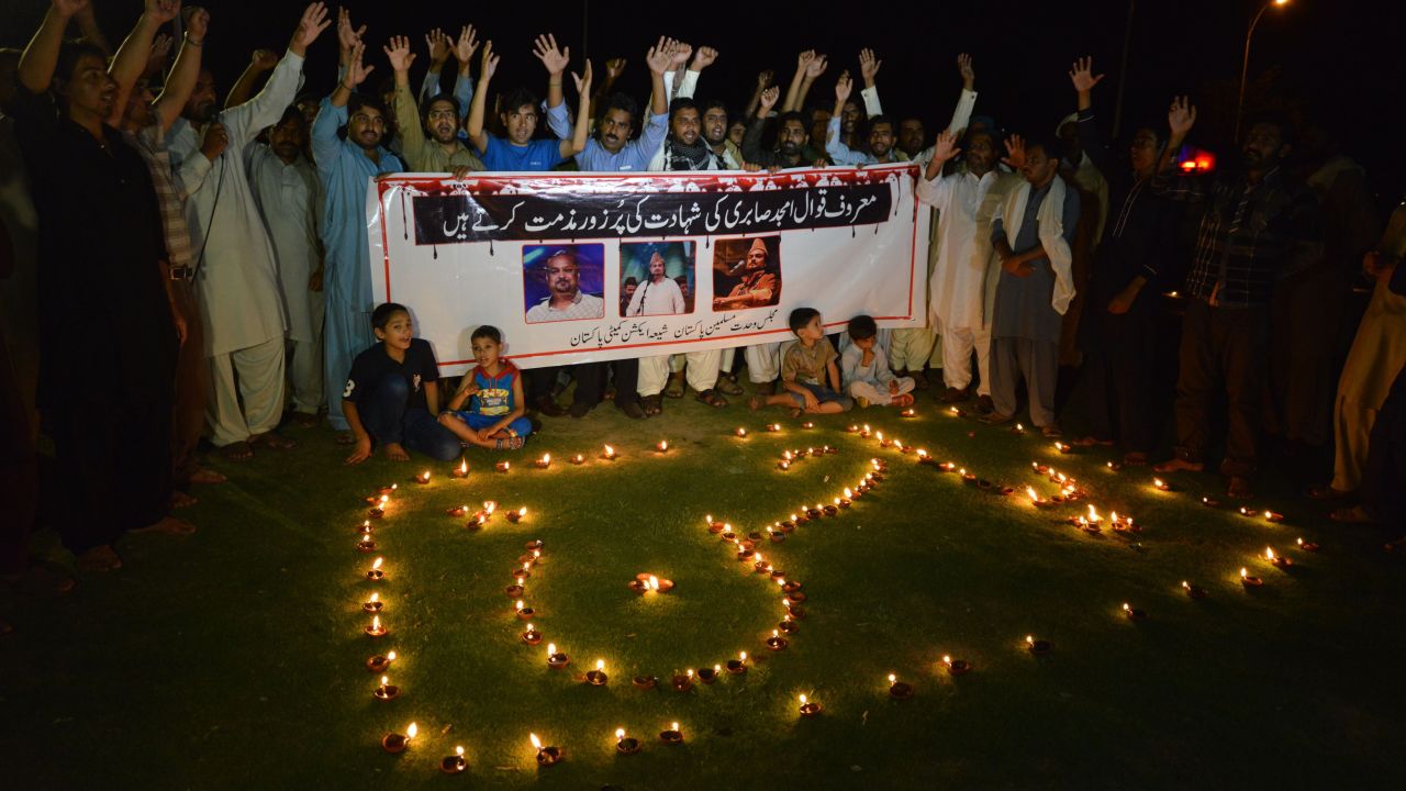 Pakistani Shiite Muslims shout slogans next to oil lamps to pay tribute to Sufi musician Amjad Sabri.