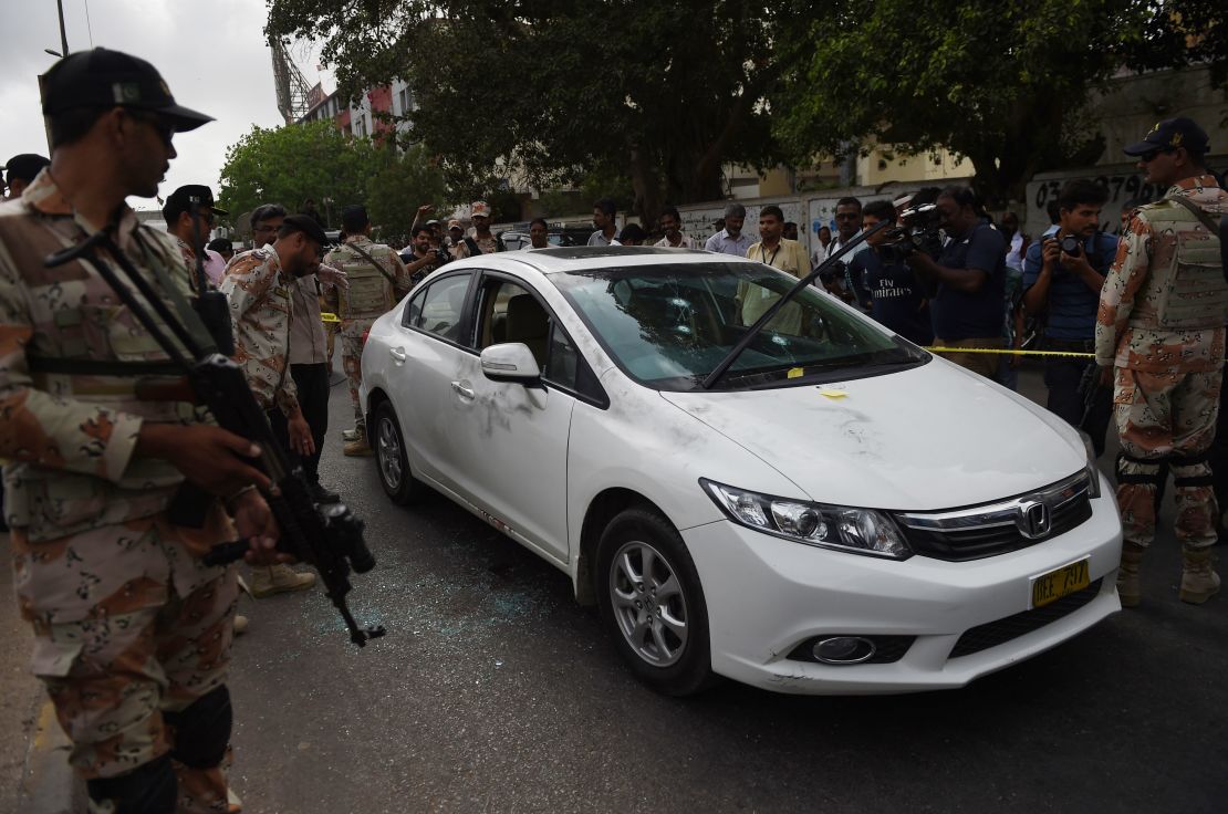 Pakistani security officials inspect the bullet-riddled car of Sufi musician Amjad Sabri. 