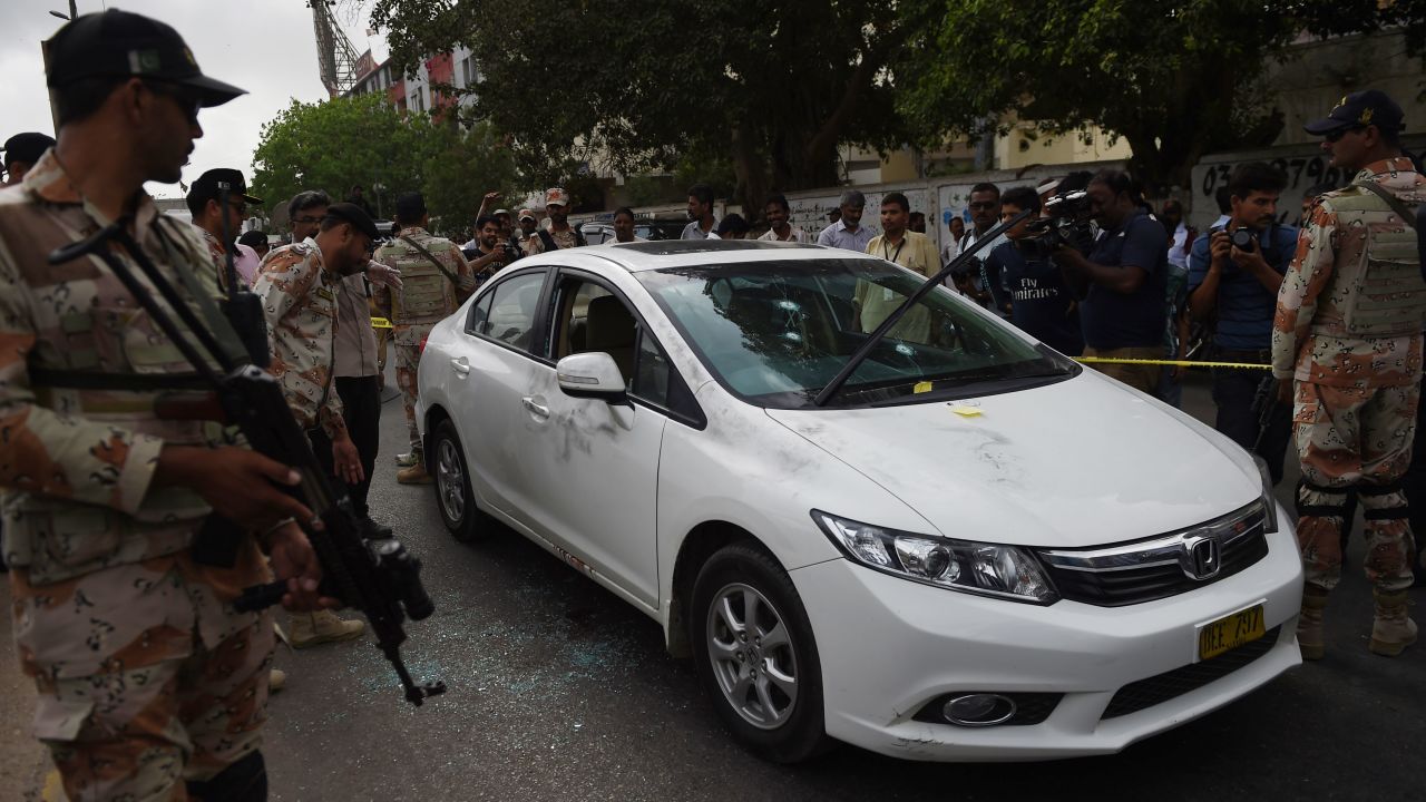 Pakistani security officials inspect the bullet-riddled car of Sufi musician Amjad Sabri.