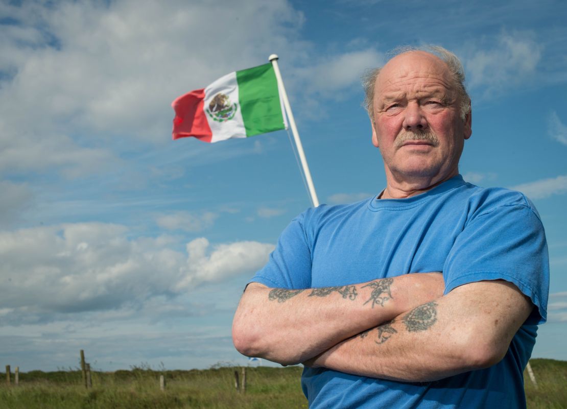 Michael Forbes poses for a photograph beside the Mexican flag he erected alongside Donald Trump's International Golf Links course, north of Aberdeen on the East coast of Scotland, on June 21.