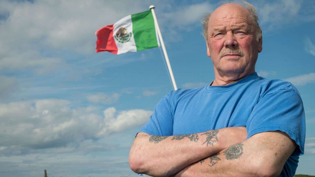 Michael Forbes poses for a photograph beside the Mexican flag he erected alongside Donald Trump's International Golf Links course, north of Aberdeen on the East coast of Scotland, on June 21.