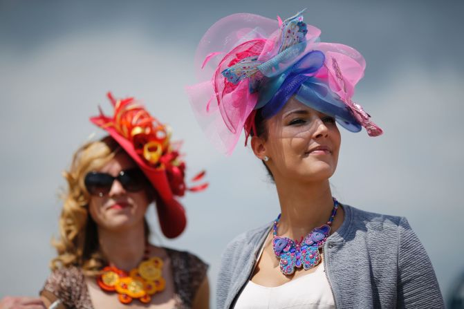 Two visitors to the 167th Prix de Diane, a flat race in Chantilly, France, provide a splash of color with their headwear.