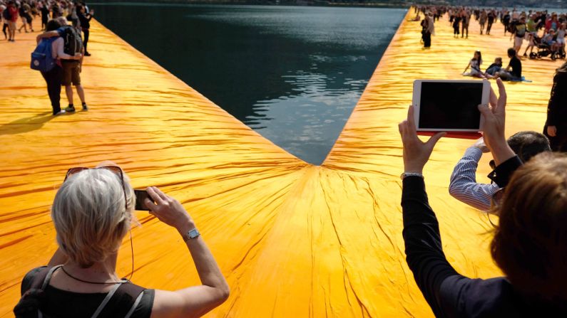 Visitors take pictures and walk across floating orange piers Saturday, June 18, as part of Christo's art project on Italy's Lake Iseo.