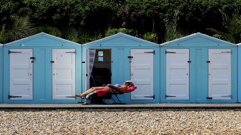 A woman enjoys the sunshine outside her beach hut in Eastbourne, England, on Sunday, June 19.