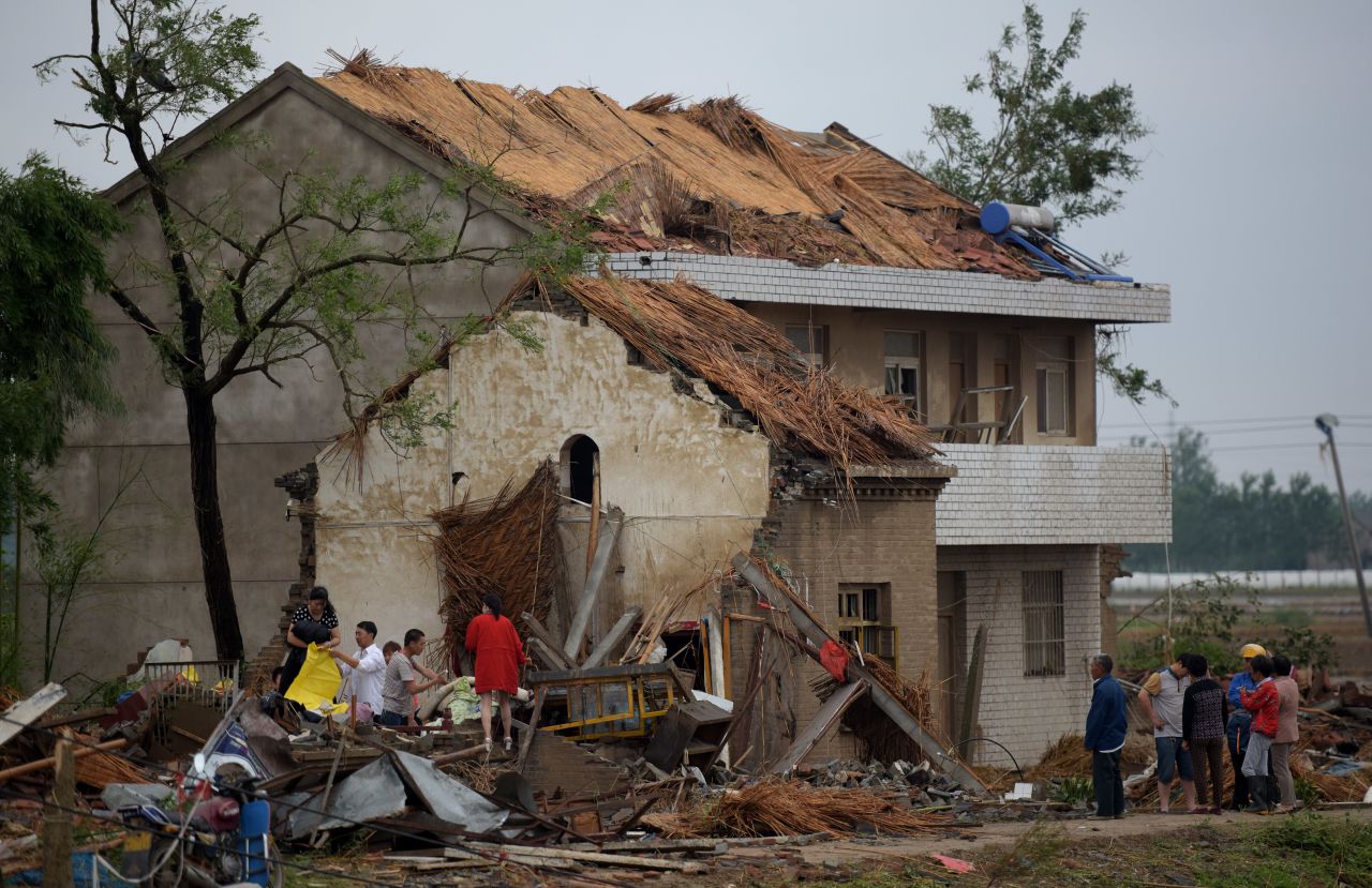 Residents survey damaged homes in Funing on June 24.