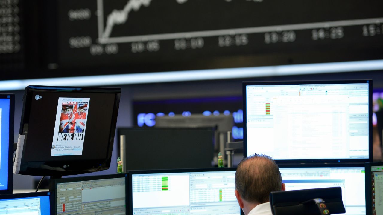 A trader sits  at his desk under the day's performance board that shows a dive in the value of the DAX index of companies at the Frankfurt Stock exchange the day after a majority of the British public voted for leaving the European Union on June 24, 2016 in Frankfurt am Main, Germany.