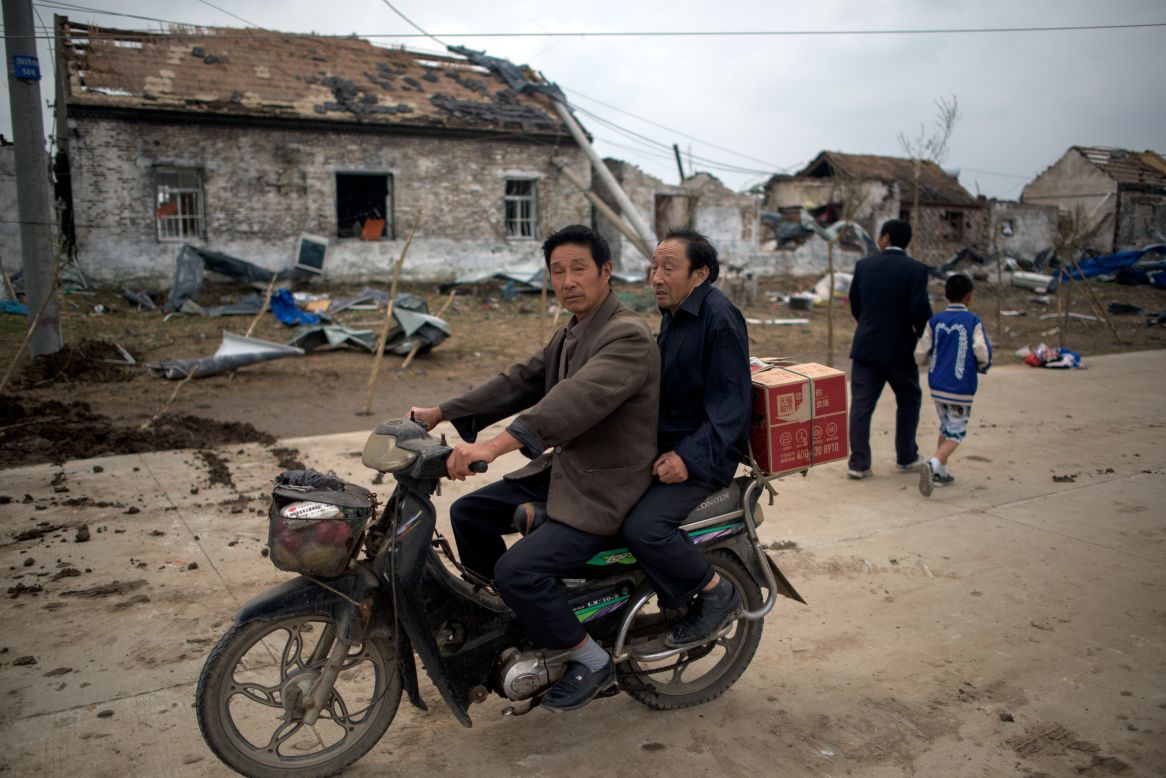 Residents on a motorbike pass through the heavily damaged village of Funing on June 24.