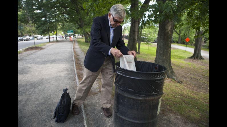 Michael Dukakis, the former Massachusetts governor who ran for President in 1988, empties a plastic bag that he filled with trash during his 2-mile walk to work on Wednesday, June 22. Dukakis is now a professor at Northeastern University in Boston, and he has long been an advocate for the environment.