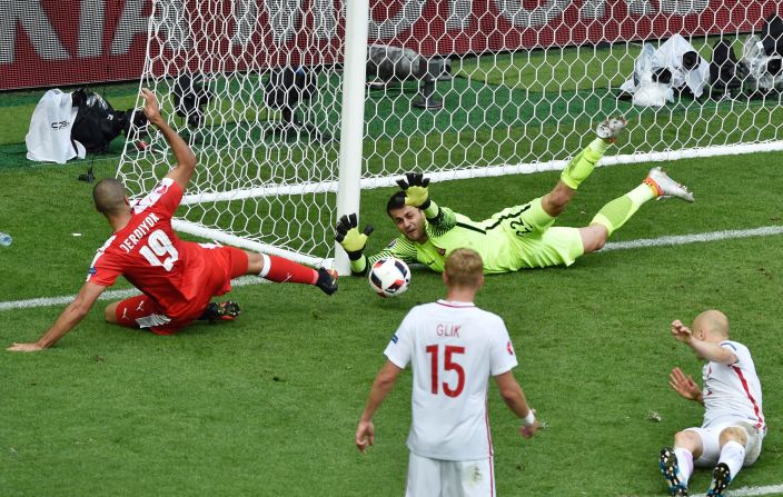 Poland goalkeeper Lukasz Fabianski, top right, saves an attempt by Switzerland forward Eren Derdiyok, left.