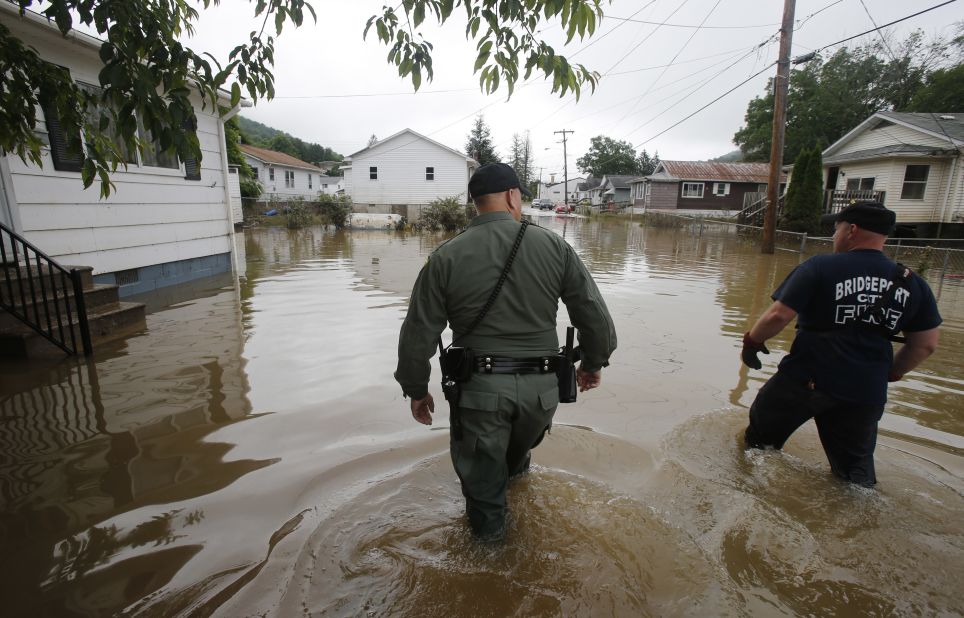 West Virginia State Trooper C.S. Hartman, left, and Bridgeport firefighter Ryan Moran wade through flooded streets as they search homes in Rainelle, West Virginia, on June 25. 