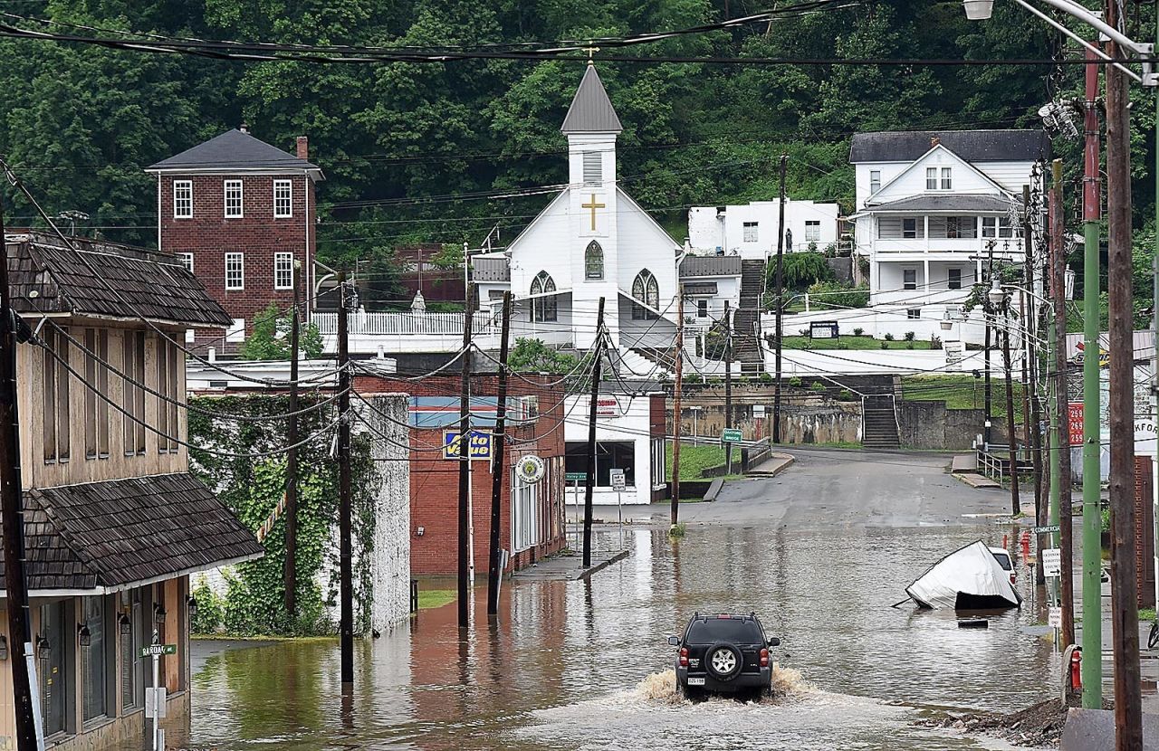 An SUV makes a wake along a flooded street in Richwood, West Virginia, on Friday, June 24.