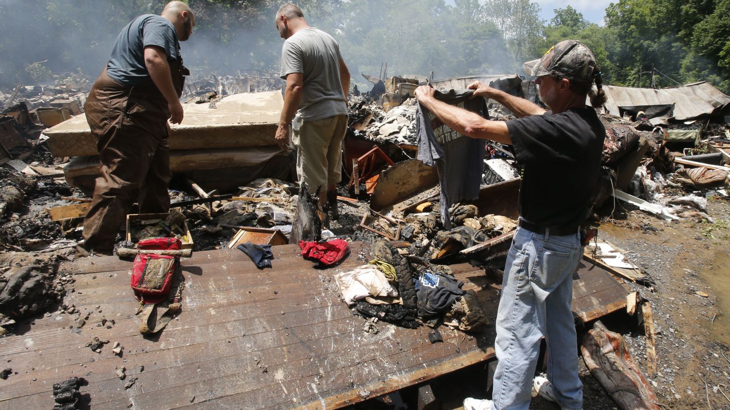 Men go through the debris of a home that washed away and burned after severe flooding hit White Sulphur Springs, West Virginia.
