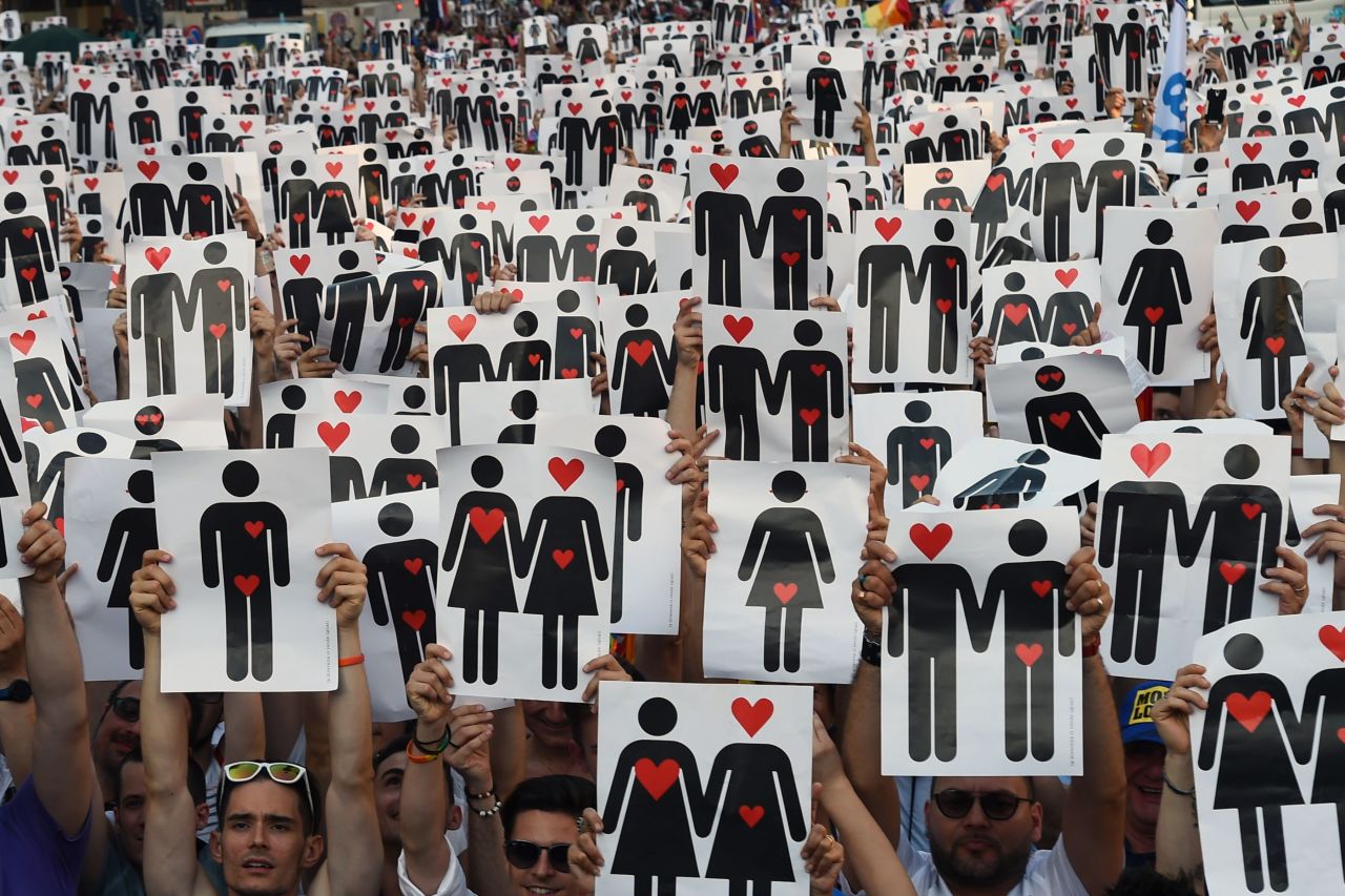 People hold placards depicting hearts and couples, during a flash mob for the annual Pride Parade in Milan, Italy, on June 25.