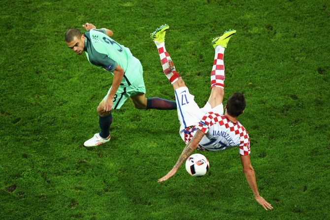 Mario Mandzukic of Croatia falls heavily while competing with Pepe of Portugal.
