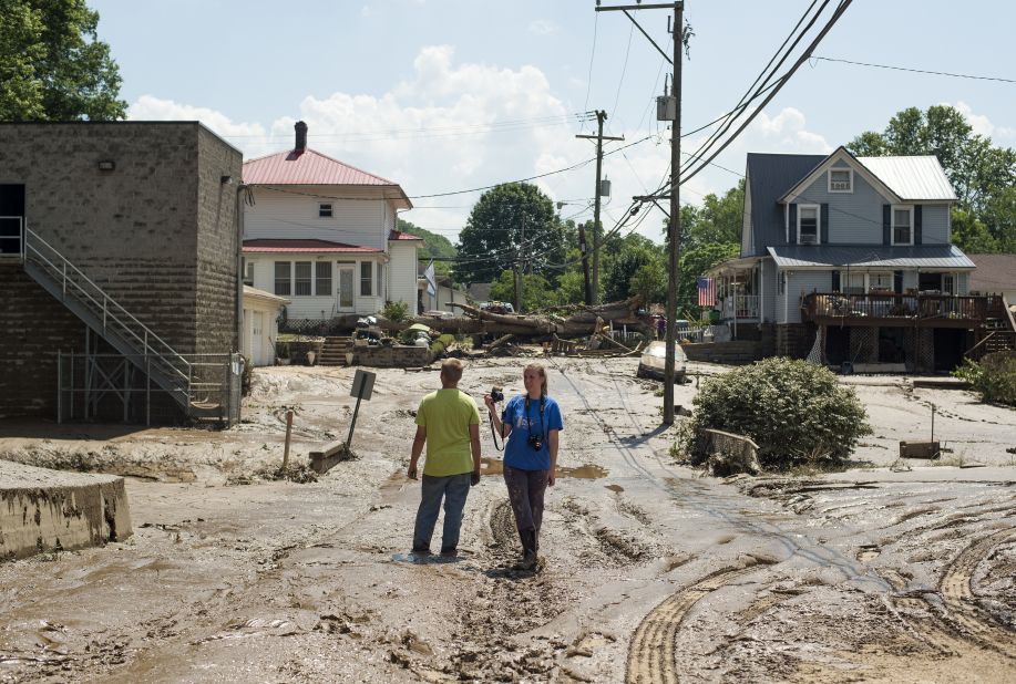 People survey a mud-covered street after the floodwaters of the Elk River receded in Clendenin on Saturday, June 25.