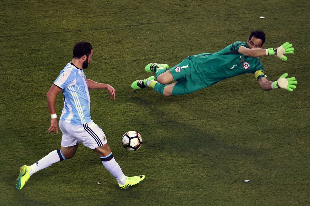 Argentina's Gonzalo Higuain, left,  prepares to shoot against Chile's goalie Claudio Bravo.