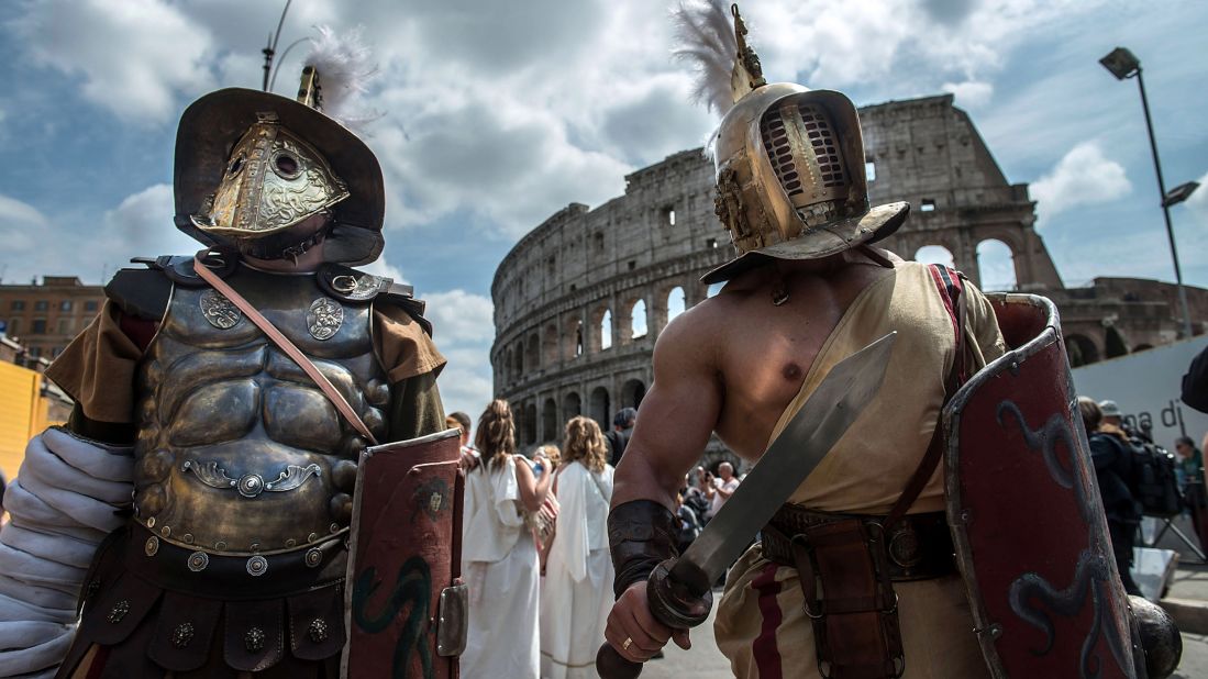 Actors dressed as ancient Roman soldiers stand near the Coliseum in eighth place Rome.