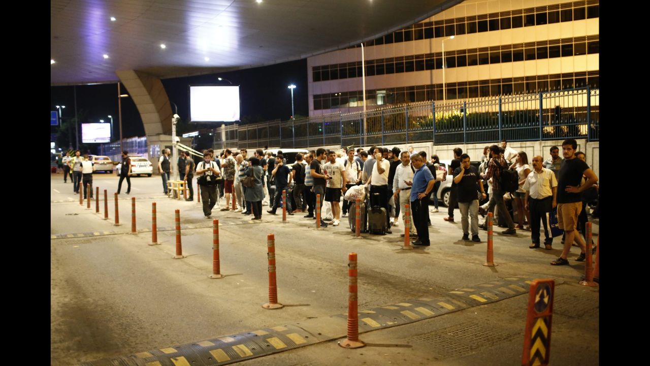 People stand outside the airport after the attack.