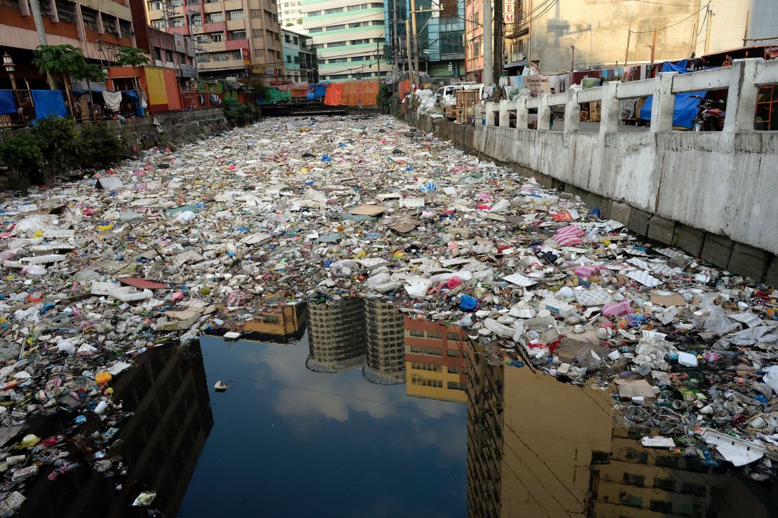 Building reflected in the waters of a garbage filled river in Manila on January 23, 2016. 