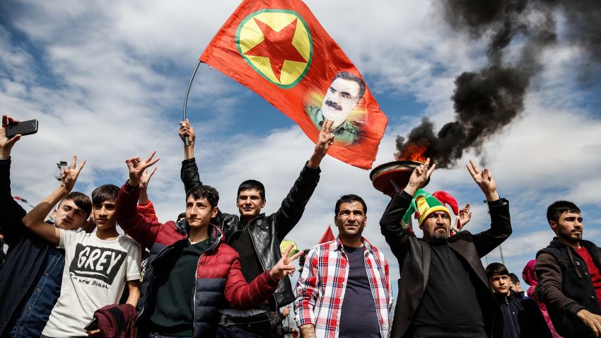 DIYARBAKIR, TURKEY - MARCH 21: Kurdish men flash v-signs as they  hold up a flag with a picture of the jailed PKK leader Abdullah Ocalan during Newroz celebrations, on March 21, 2015 in Diyarbakir, Turkey. Thousands of Kurds gather for the Newroz spring festival in Diyarbakir in southeast Turkey under tight security after months of fighting between security forces and Kurdish separatists, and a series of bombings in Istanbul and Ankara. (Photo by Ulas Tosun/Getty Images)