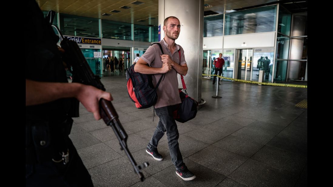 A police officer stands guard as a man walks at the airport a day after the attack.