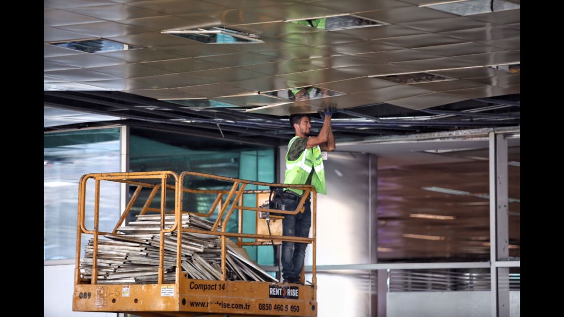 A worker repairs the airport's damaged ceiling on June 29.