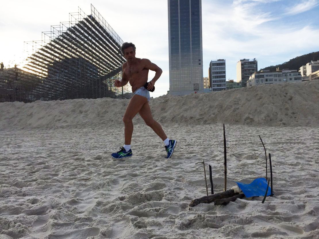 A runner passes by the body parts that were found near the Olympics beach volleyball stadium, visible in the background.