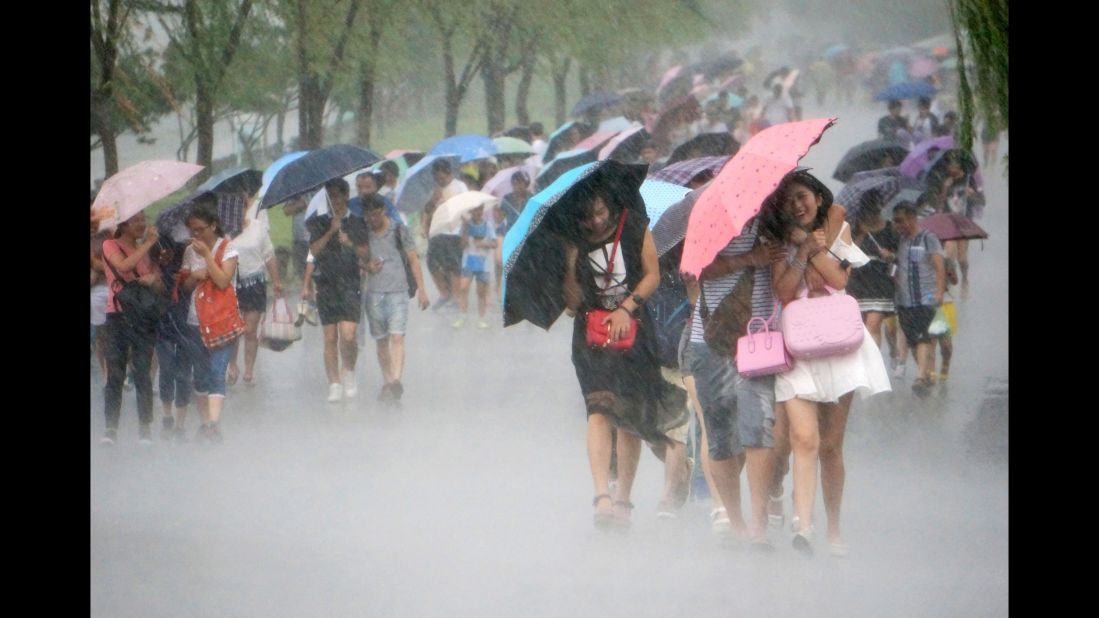 People in Hangzhou, China hold umbrellas sideways as they fight strong winds and heavy rain from Typhoon Soudelor in 2015.