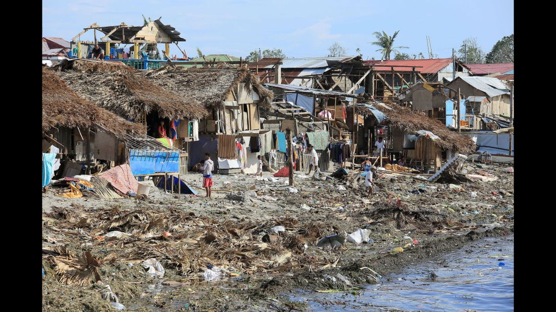 Residents stand next to their damaged houses with blown out roofs after typhoon Melor hit Bulan town, Sorsogon province, south of Manila on December 15, 2015. Tattered lanterns, festive lights and tin roofs littered towns in the central Philippines on December 15 after Typhoon Melor swept through, killing at least four people and leaving millions without power ahead of Christmas. 