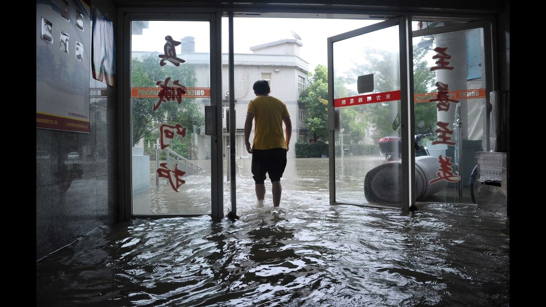 A man walks out through the doors of a flooded building after strong rains hit Shanghai on August 24, 2015. Heavy rains brought by a cold front and enhanced by passing Typhoon Goni brought flooding to many districts across Shanghai.   