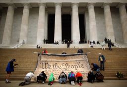 Volunteers help roll up a giant banner printed with the Preamble to the Constitution.