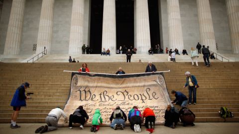Volunteers help roll up a giant banner printed with the Preamble to the Constitution.